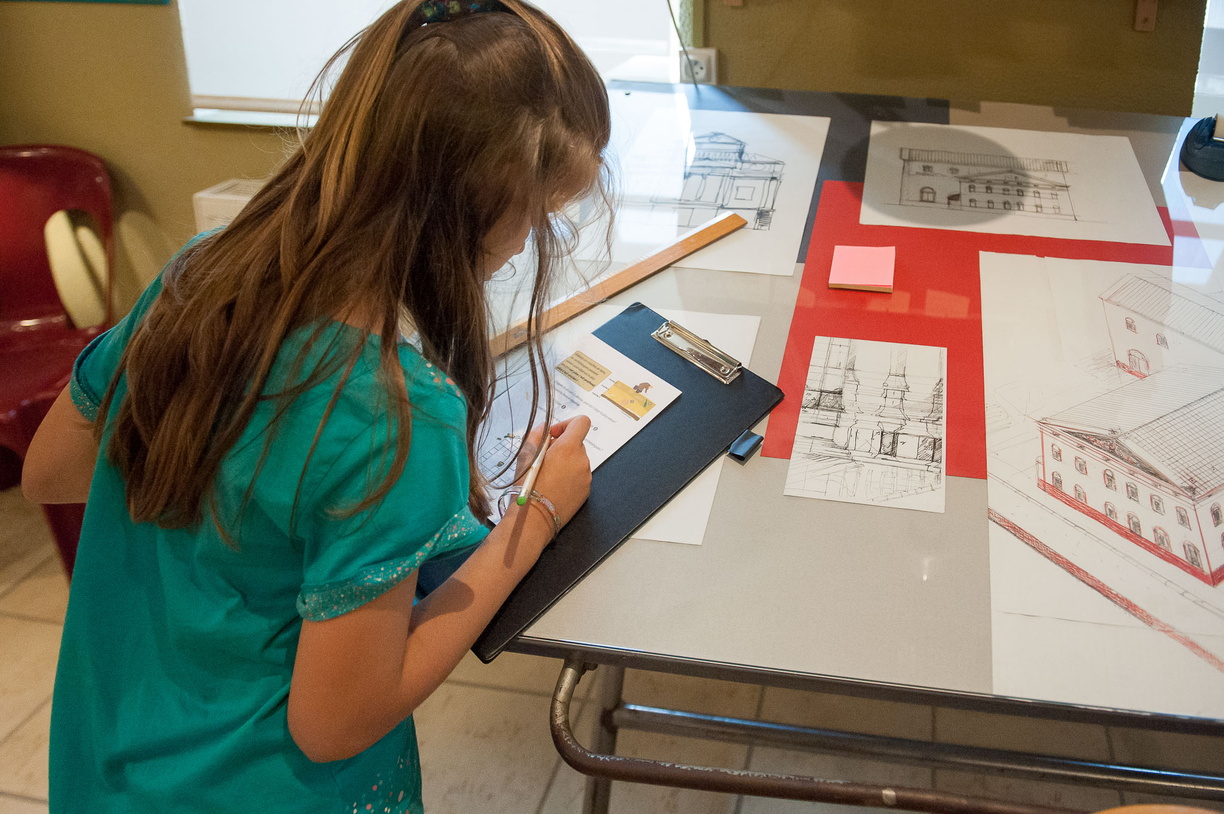 Une enfant est passionnée par son livret jeu, elle le complète assidument.
