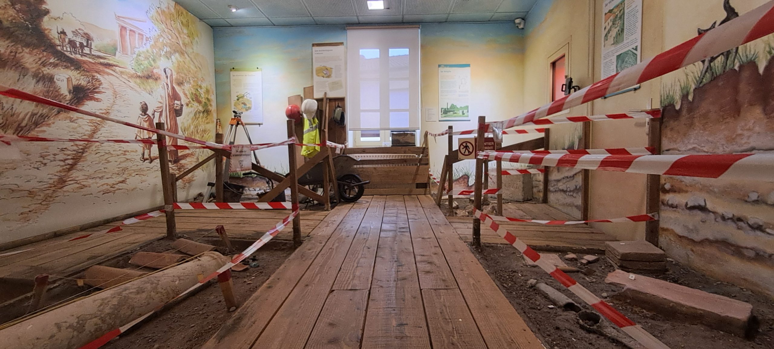 Photo d'ambiance de la première salle du musée. Présentée comme un chantier de fouilles, les objets archéologiques côtoient les outils des archéologues.